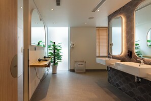 A modern bathroom with two sinks, a large mirror, and a potted plant. - MEANDER Saigon (Ho Chi Minh City)