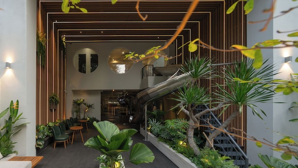 A modern interior with a central staircase, indoor plants, and a seating area. - MEANDER Saigon (Ho Chi Minh City)