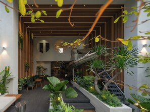 A modern interior with a central staircase, indoor plants, and a seating area.