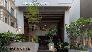A modern building entrance with a staircase leading up to a door, surrounded by greenery and a sign that reads 'MEANDER.' - MEANDER Saigon (Ho Chi Minh City)
