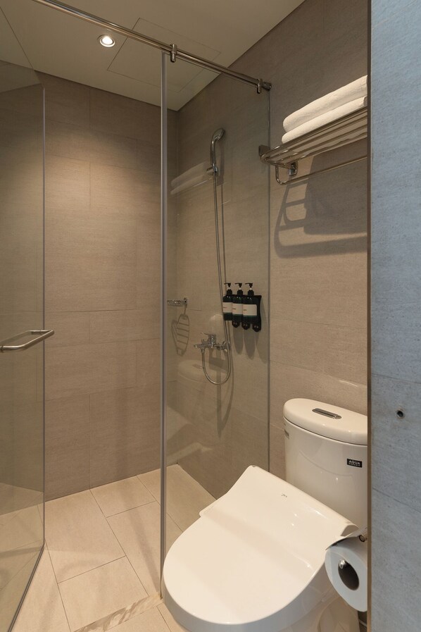 A modern bathroom with a glass-enclosed shower, a white toilet, and a towel rack.