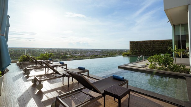Ein Rooftop-Pool mit Liegestühlen und Blick auf die Stadt.