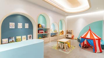 Children can play and create in this vibrant playroom with a reception desk, shelves, and a cozy play structure.