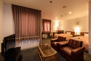 Habitación de hotel con televisión, dos camas, escritorio, silla y una mesita.