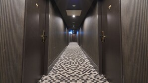 A hallway with dark wooden doors, a checkered floor, and recessed lighting. - Hotel Vine Osaka Kitahama (Osaka)