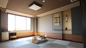Een traditionele Japanse kamer met tatami vloeren, een lage tafel met kussens, een houten kast en een schuifdeur.