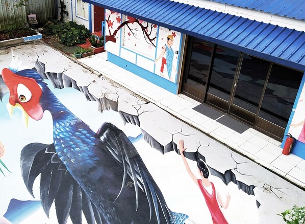 Un bâtiment orné d’une fresque représentant un grand oiseau et une personne tendant la main.
