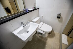Un baño moderno con un lavamanos, inodoro y espejo sobre el lavamanos.