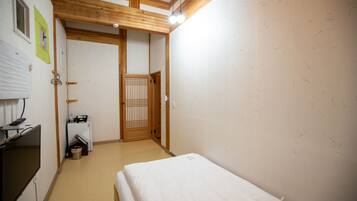 Habitación de hotel con cama, escritorio con computadora, televisión y una kitchenette pequeña.