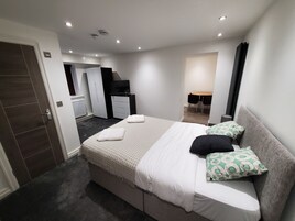 Un dormitorio moderno con una cama grande, un escritorio y una zona de comedor.