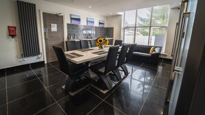A modern kitchen with a dining table, chairs, and a sofa. - The Ashcroft Apartments (Manchester)