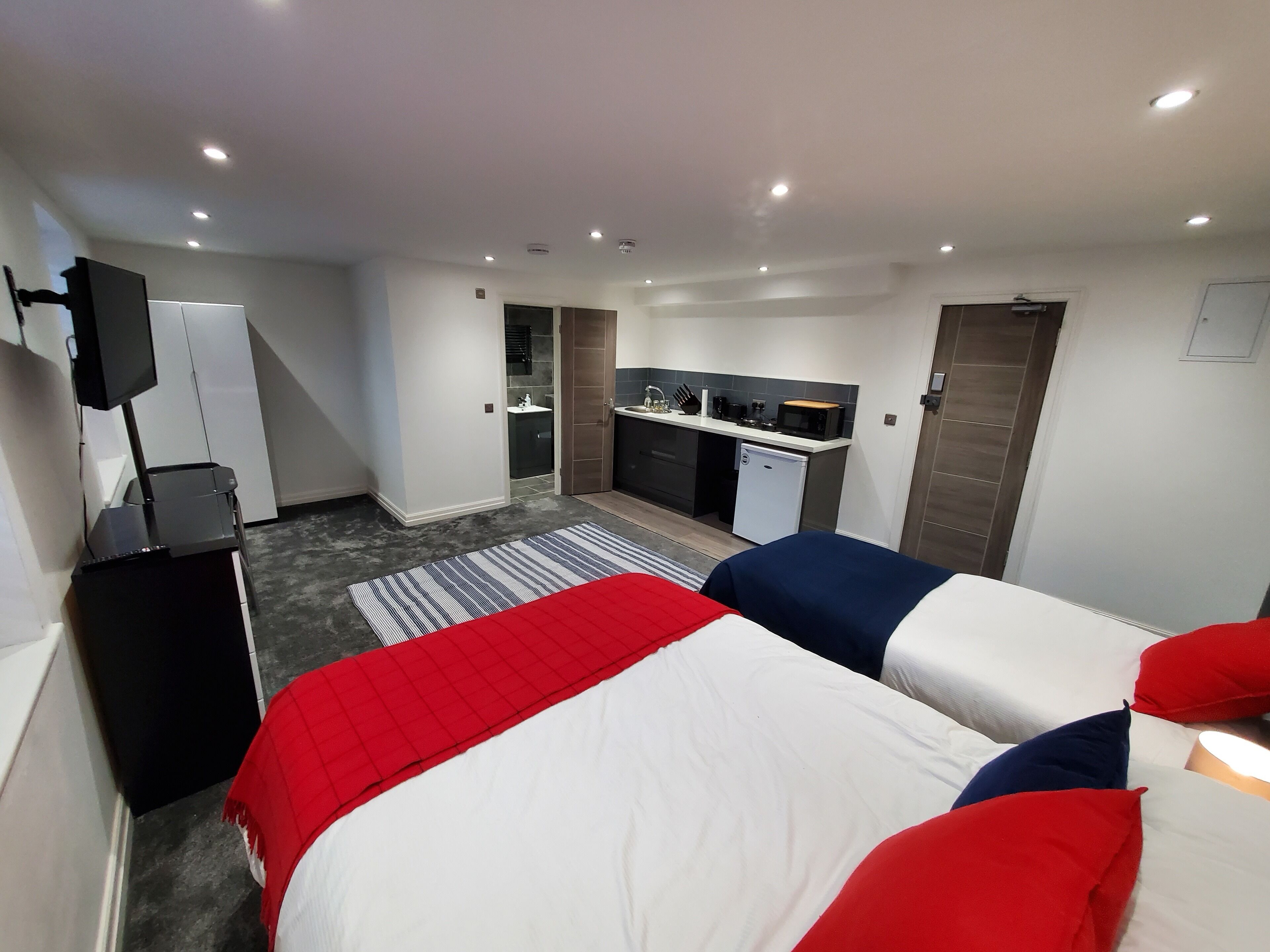 Ein Hotelzimmer mit Bett, Fernseher, Küchenzeile und Badezimmer.