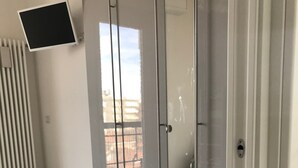 A room with a sliding glass door, a radiator, a grey floor, and a small rug. - Wonderful apartment in quiet residential complex. (Cattolica)