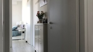 A narrow hallway with a bed, bedside table, and a cabinet with a vase of flowers. - Wonderful apartment in quiet residential complex. (Cattolica)