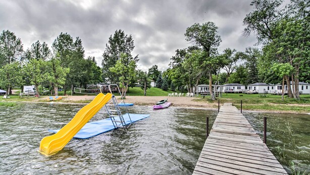 A water park with a wooden deck, a yellow slide, and a blue platform. - Lovely Lake Cabin: Boat Rentals & On-Site Bar (Dent)