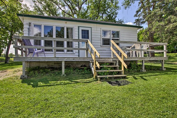 A small, single-story cabin with a porch, wooden steps, and a few chairs.