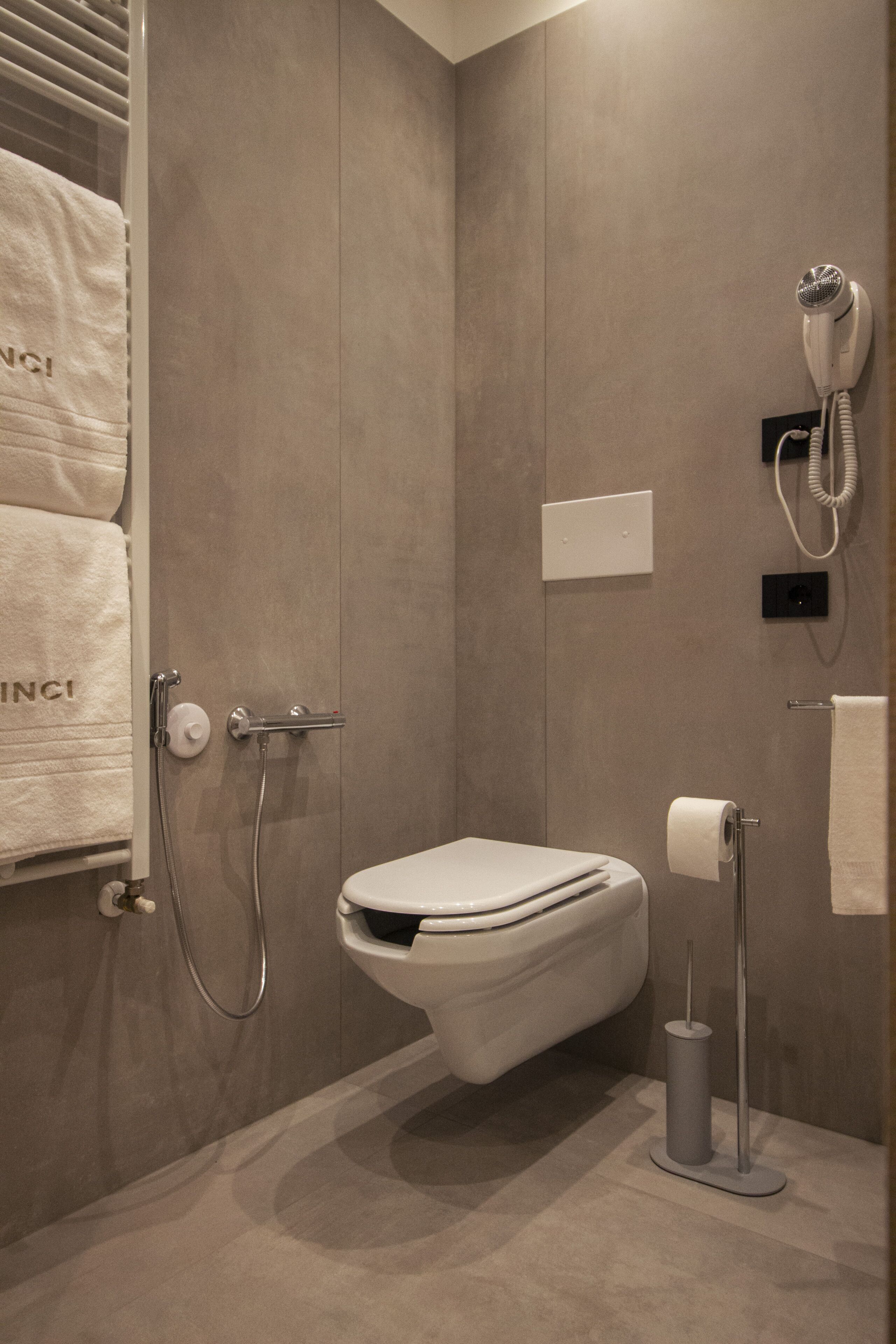 Un baño moderno con ducha integrada, inodoro y secador de pelo montado en la pared.