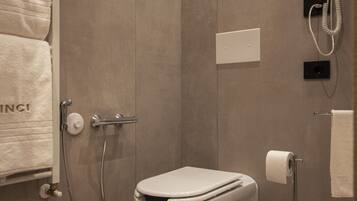 Een moderne badkamer met een inloopdouche, toilet en een aan de muur bevestigde haardroger.