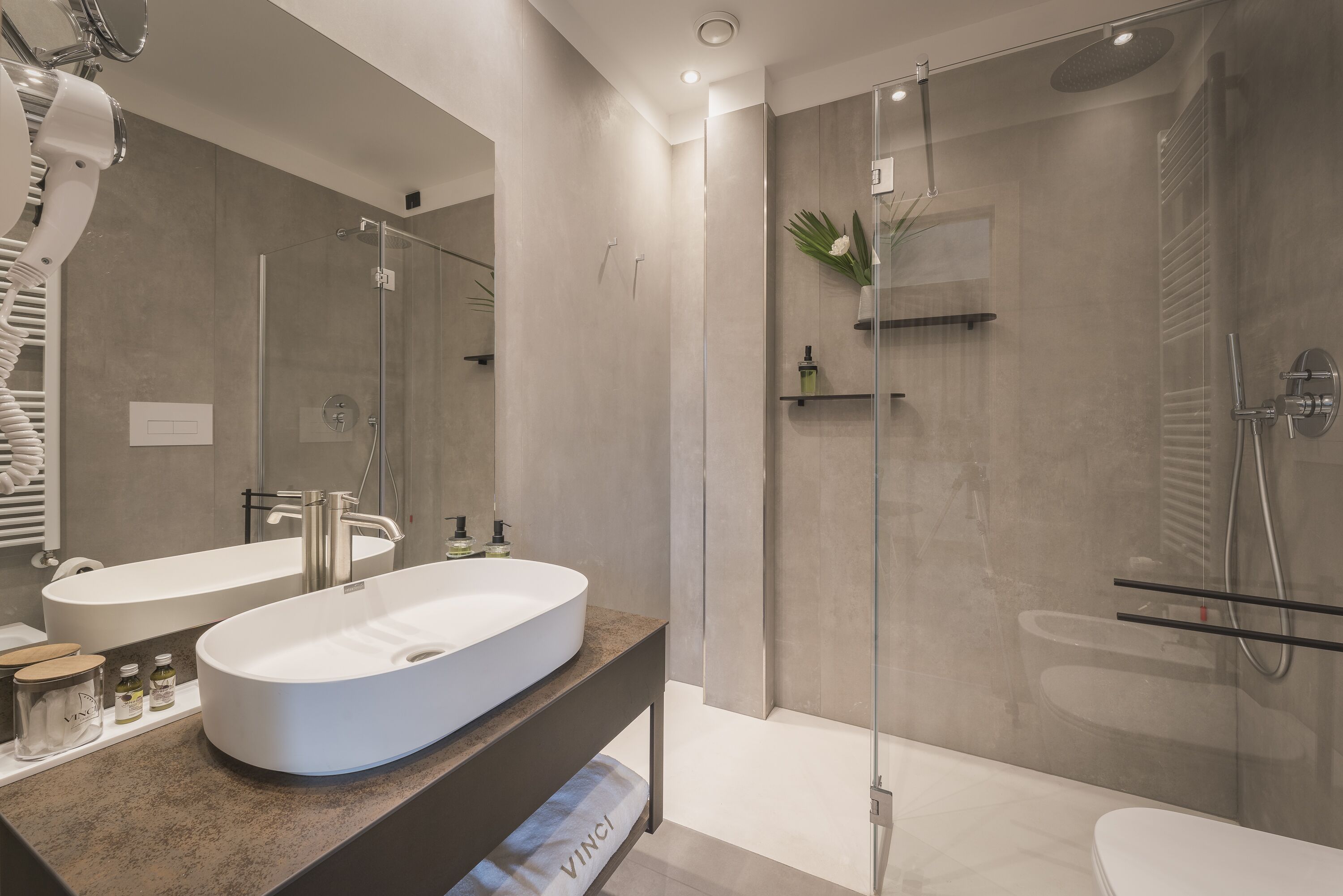 Un baño moderno con un lavamanos ovalado grande, una cabina de ducha de vidrio y un inodoro.