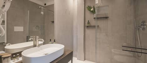 Un baño moderno con un lavamanos ovalado grande, una cabina de ducha de vidrio y un inodoro.