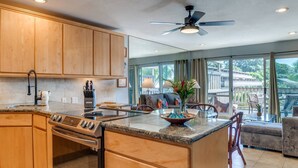 Une cuisine spacieuse avec des meubles en bois, un îlot central et un ventilateur de plafond.