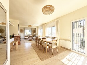 A spacious living area with a dining table, chairs, a sofa, and a fireplace.