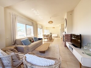 A spacious living area with a sofa, dining table, and TV.
