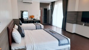 Une chambre d’hôtel avec deux lits, un bureau, une télévision et une grande fenêtre avec des rideaux.