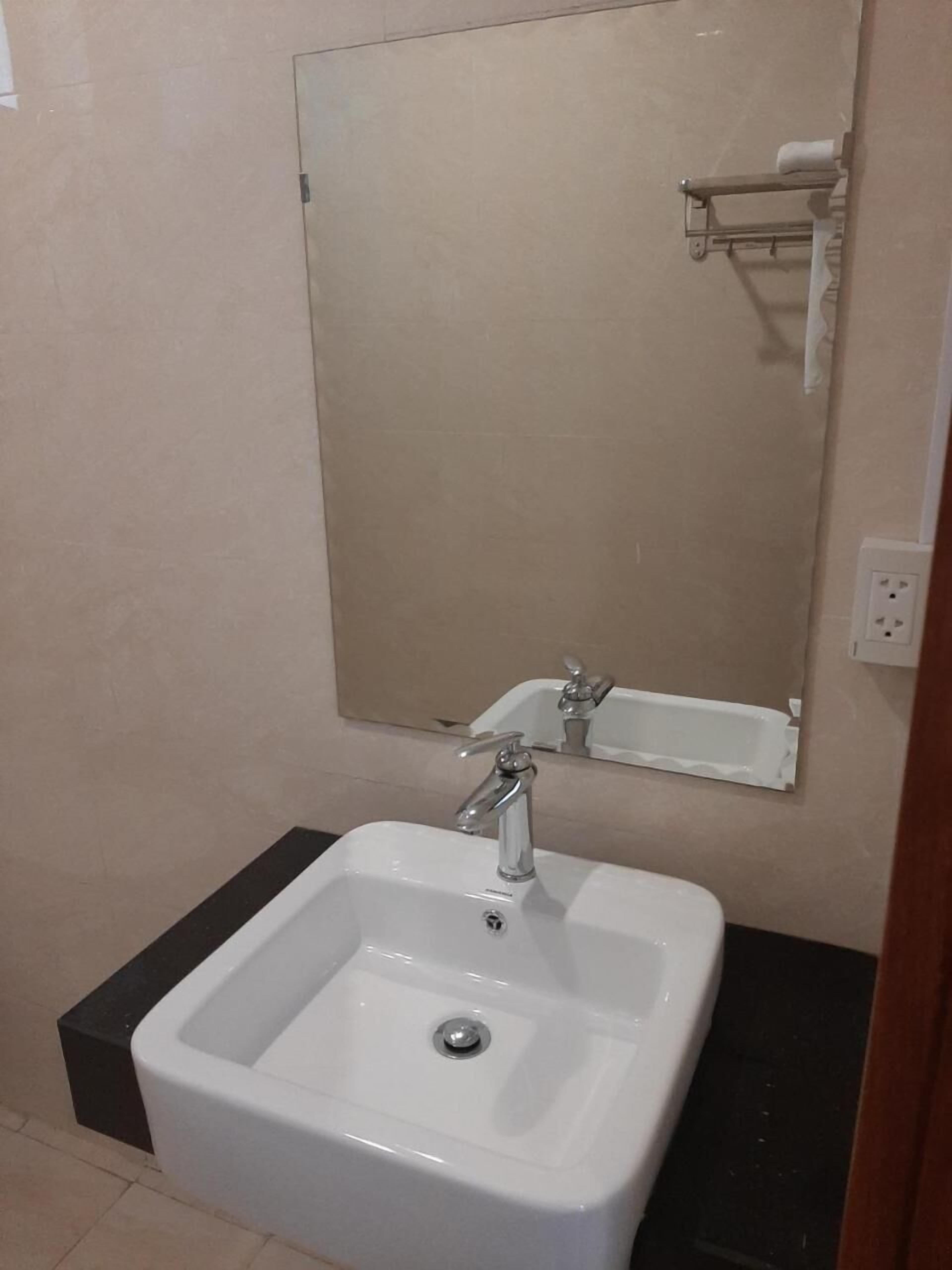A bathroom with a white sink, a mirror, and a towel rack.