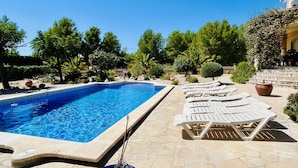 A swimming pool with lounge chairs and a stone patio. - Oasis extensive grounds, large pool (Ametlla de Mar)
