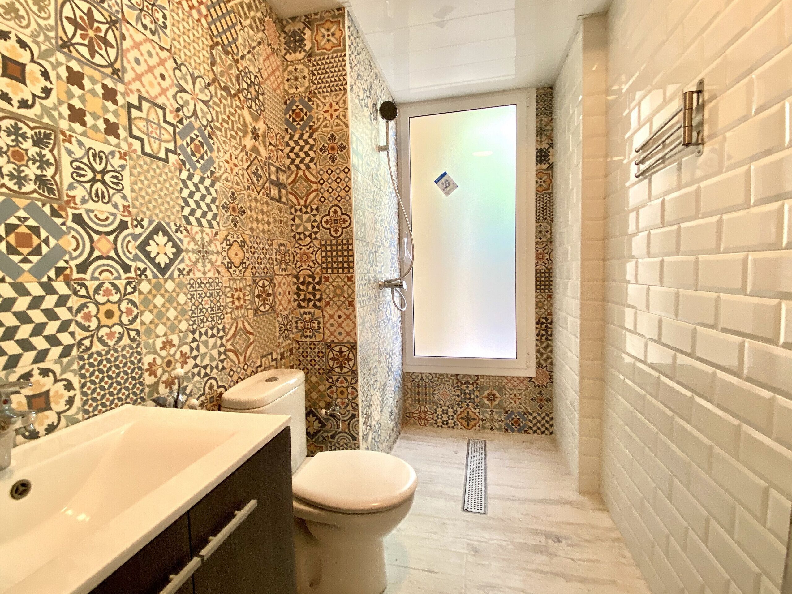 A bathroom with patterned tiles, a white sink, and a toilet.