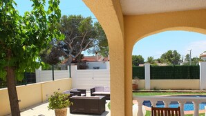 A covered outdoor seating area with a pool in the background. - Villa Esperanza well equipped, ideal for families (L'Ametlla de Mar)