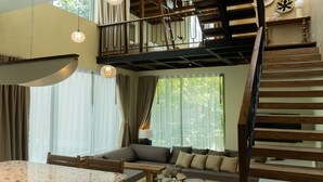 A spacious living area with a wooden staircase, a sofa set, and a dining table. - Seamira House Huahin (Hua Hin)