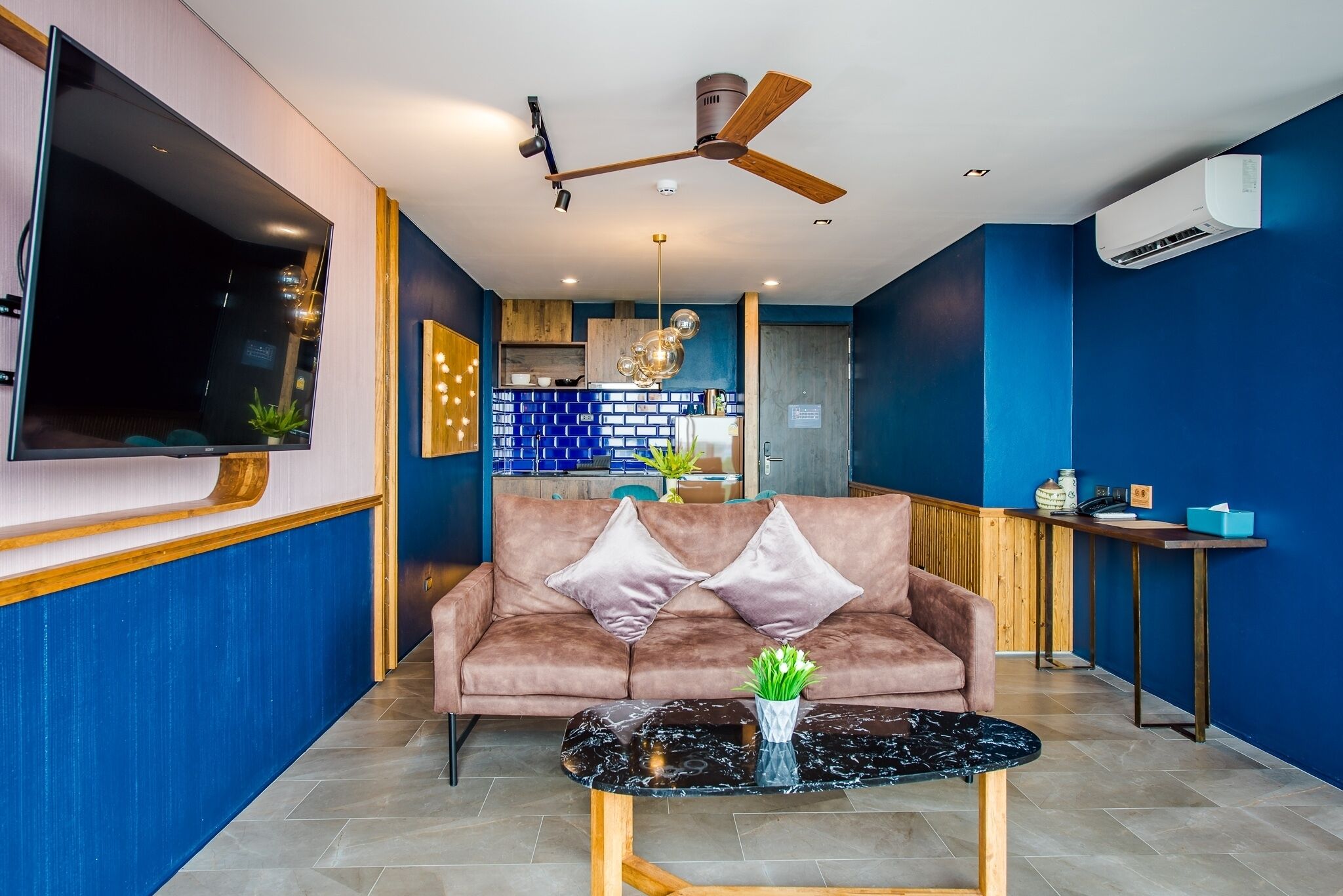 A modern living room with a sofa, coffee table, and a TV mounted on the wall.
