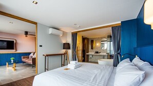 A modern hotel room with a large bed, a desk, a chair, a TV, and a bathroom visible through an open door. - Seamira House Huahin (Hua Hin)
