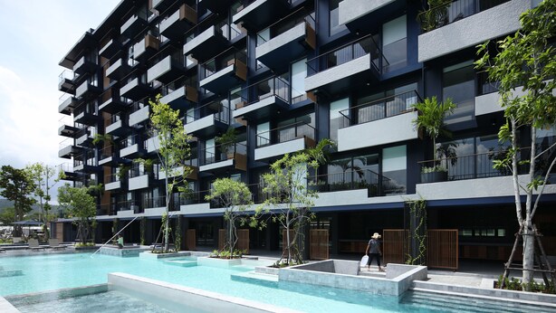 A modern multi-story building with balconies, a swimming pool, and surrounding greenery. - Seamira House Huahin (Hua Hin)