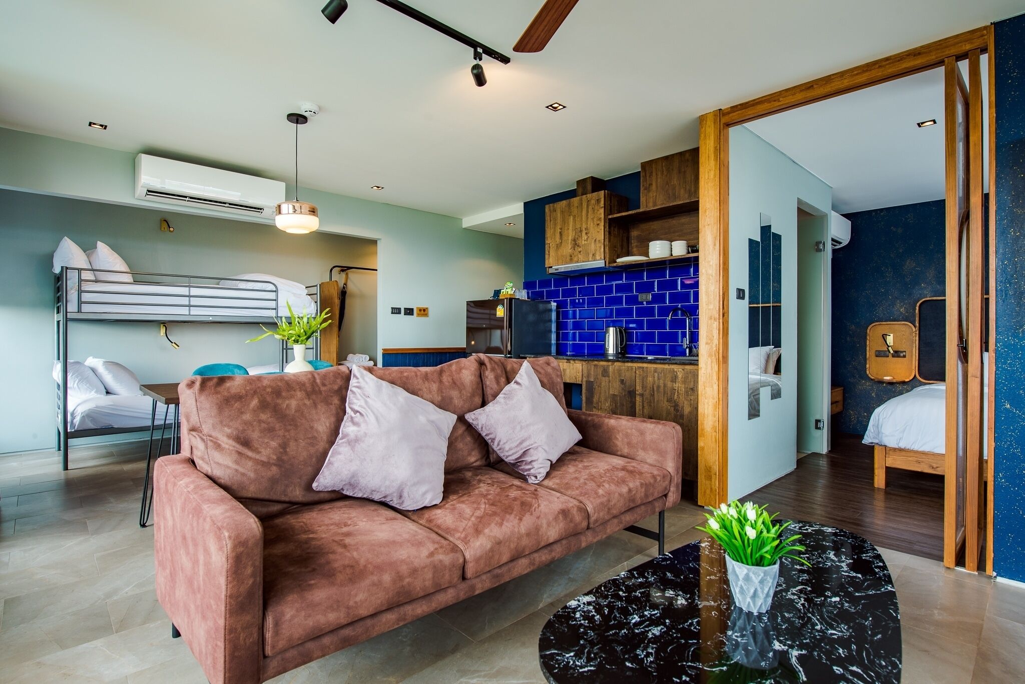 Uma sala de estar moderna com um sofá, uma mesa de centro e uma área de cozinha com azulejos azuis.