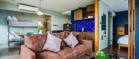 Uma sala de estar moderna com um sofá, uma mesa de centro e uma área de cozinha com azulejos azuis.