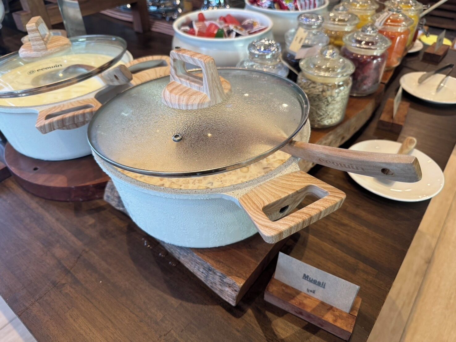 A buffet setup with various food containers and utensils.
