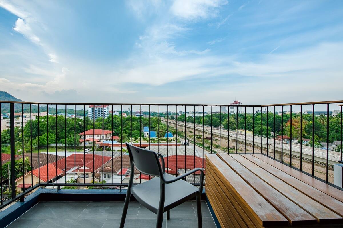 A balcony with a view of a cityscape, including buildings and a bridge.