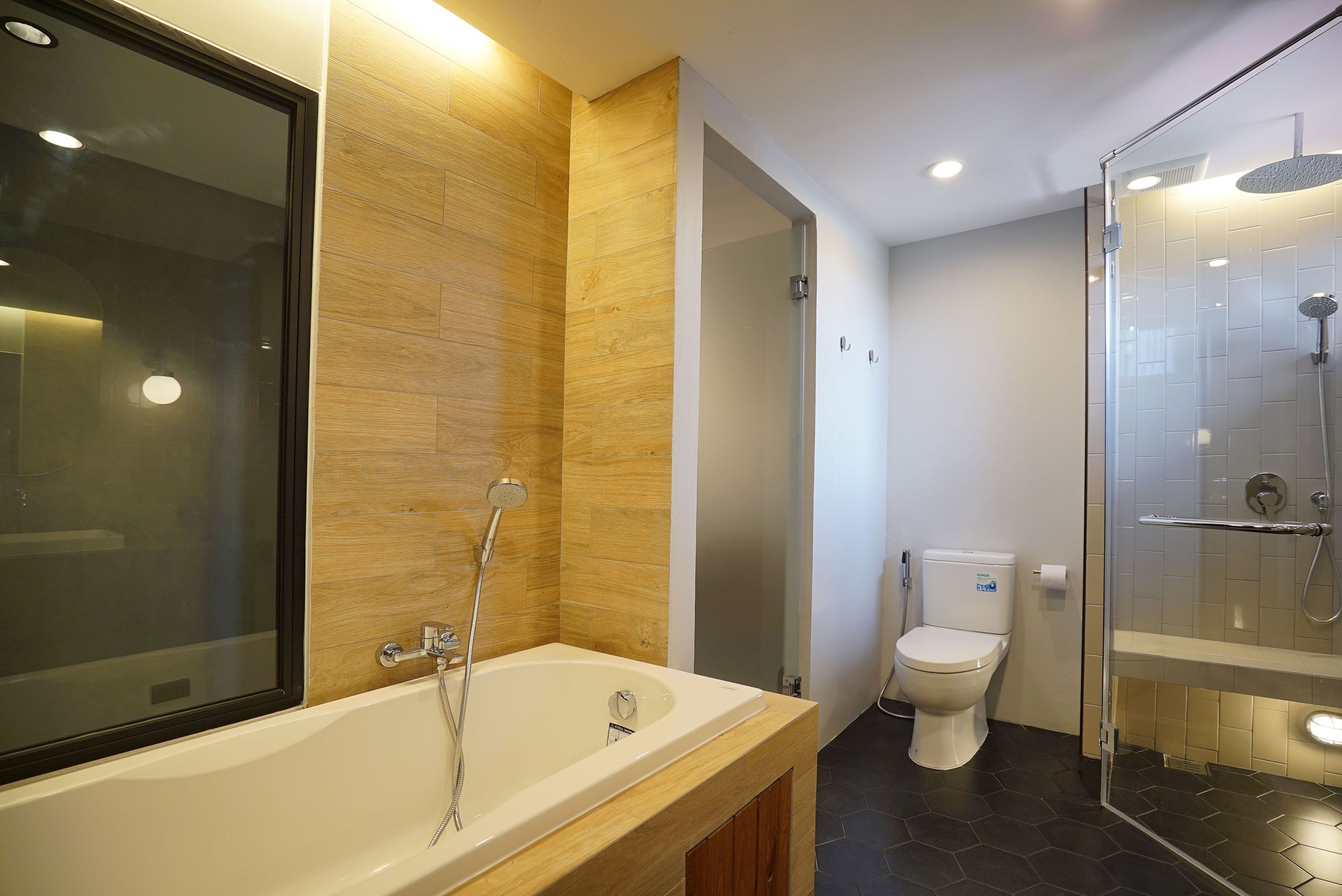 A modern bathroom with a bathtub, toilet, and glass-enclosed shower.
