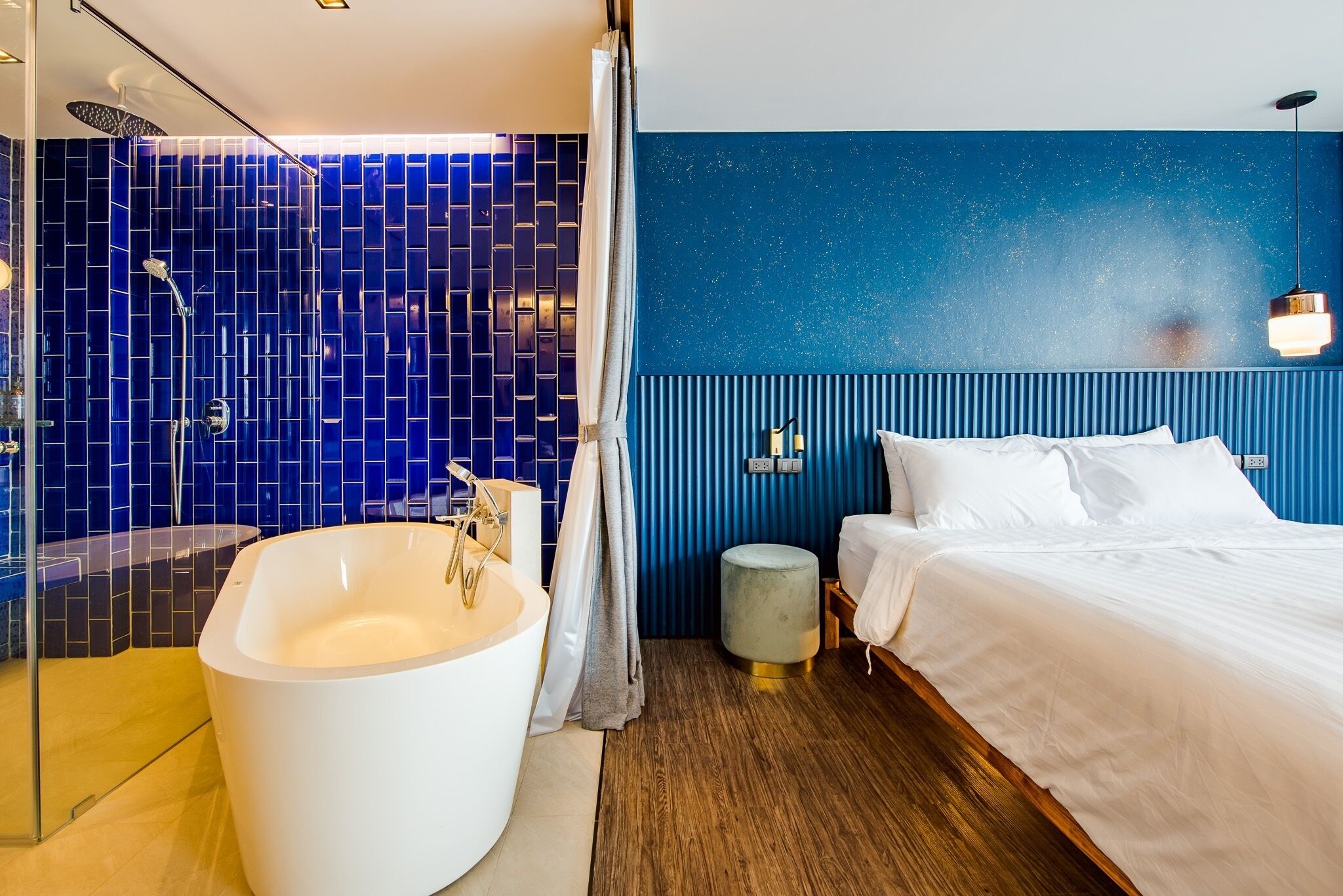 A modern bathroom with a large bathtub, a shower area, and a blue-tiled wall.
