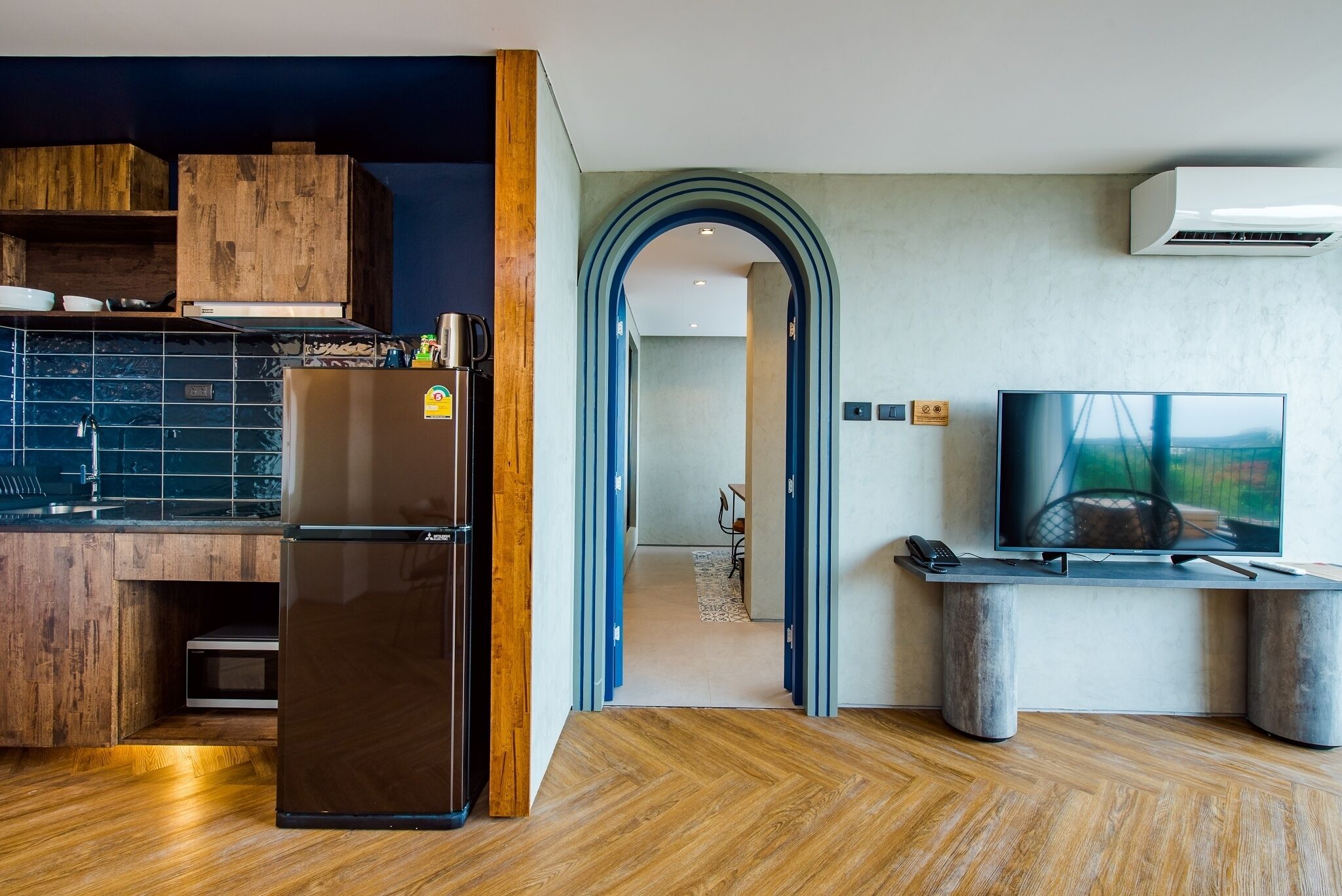 Une cuisine moderne dotée d’un réfrigérateur encastré, de meubles en bois et d’un crédence en carreaux noirs.