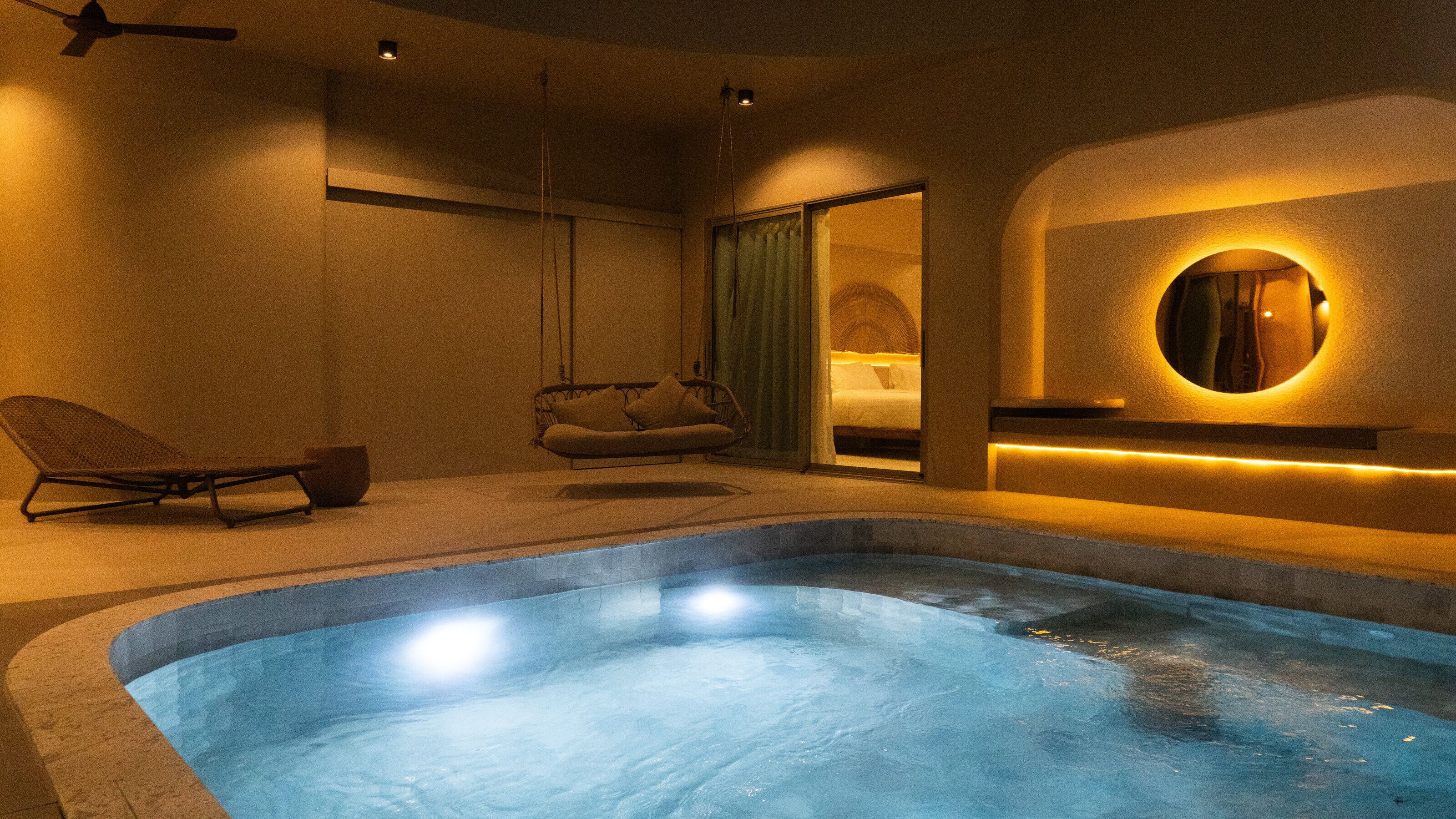 Un moderno cuarto de spa con una tina de hidromasaje, un sillón colgante y una zona de estar acogedora.