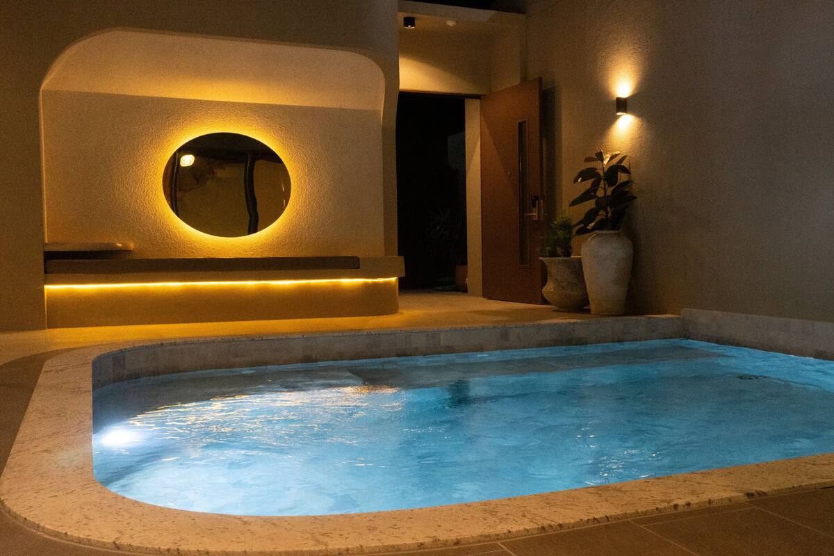 A spa area with a hot tub, a circular mirror, and a wall-mounted light fixture.