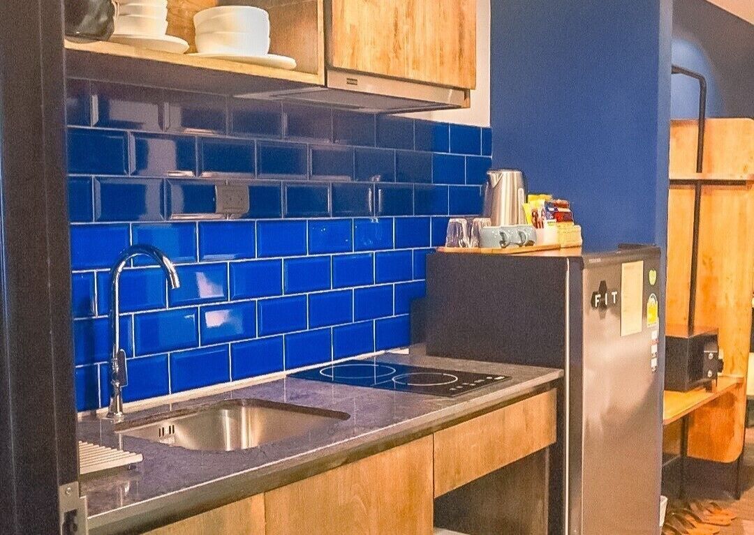 Uma cozinha compacta com azulejos azuis, eletrodomésticos de aço inoxidável e armários de madeira.