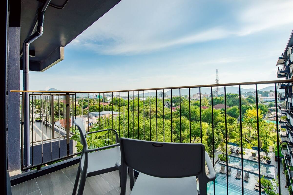 A balcony with a view of a swimming pool and greenery.