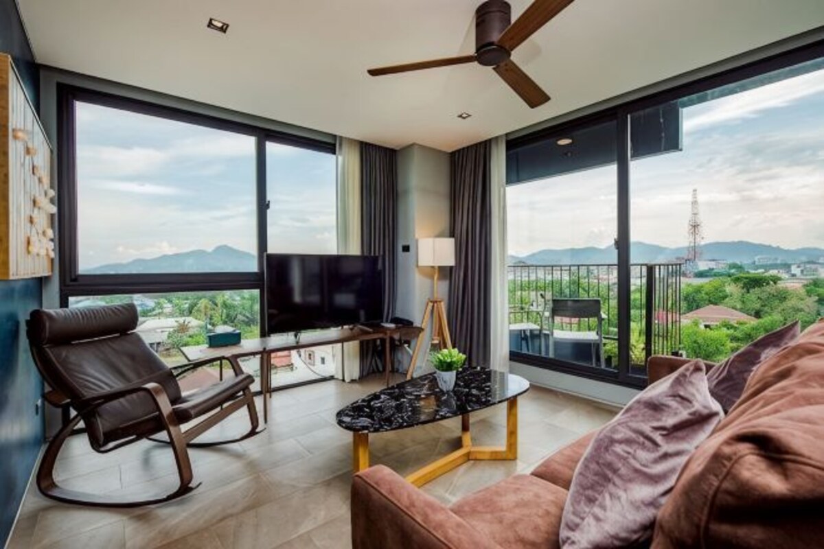 Una sala de estar moderna con un sofá, una mesa de centro, un televisor y un balcón con vistas a la ciudad.