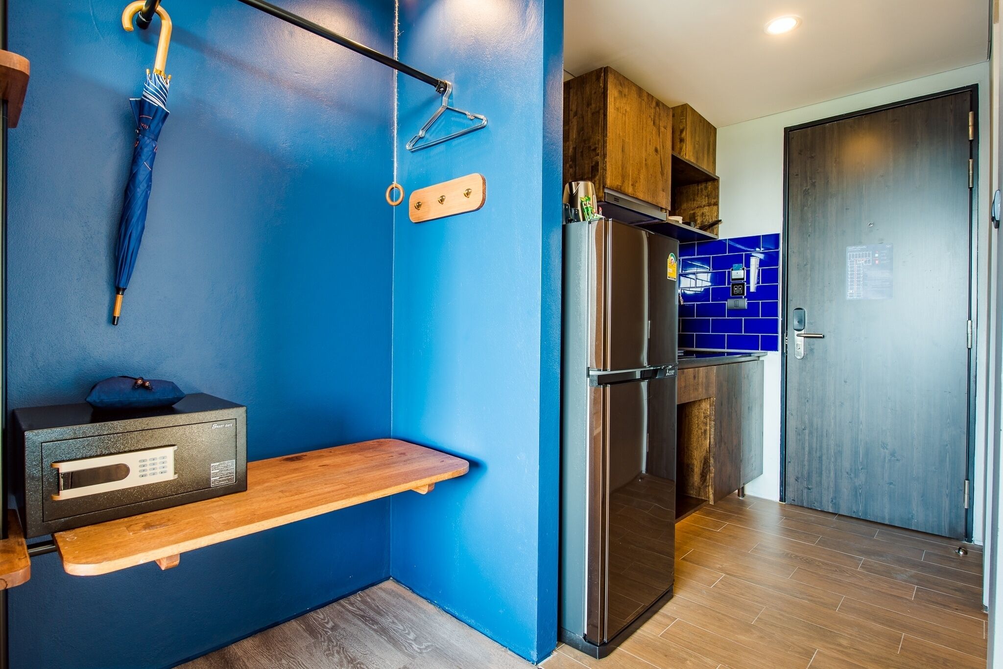 Een moderne keuken met blauwe wanden, een houten plank, een roestvrijstalen koelkast en een houten kast.