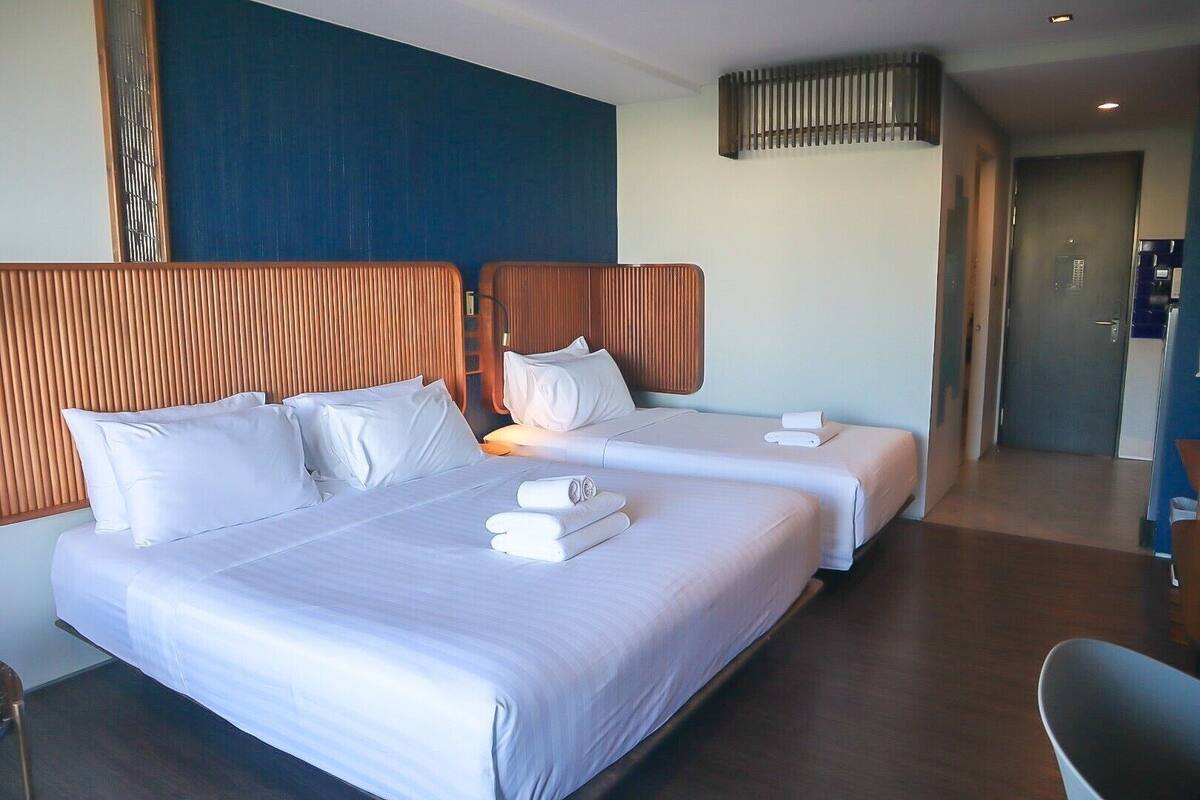 A hotel room with two beds, wooden headboards, and a modern design.